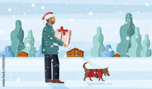 Man walking the dog in the snow while holding gift box. Snowing outside. Wint...