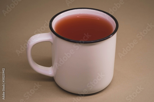 white mug with red tea on a dull brown background