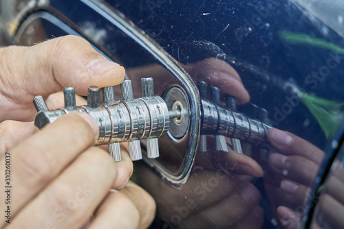 Locksmith opening with the lockpicker a blue car that its owner has lost the keys
