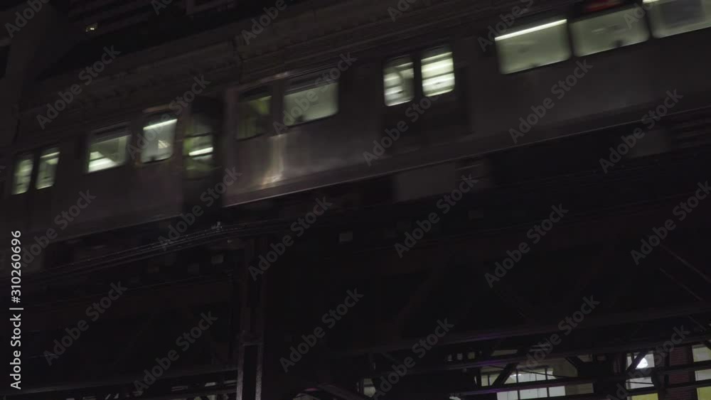 Typical Chicago night time establishing shot of generic downtown urban apartment building along L train tracks as trains pass by outside loft windows Typical Chicago night time establishing shot of generic downtown urban apartment building along L train tracks as trains pass by outside loft windows