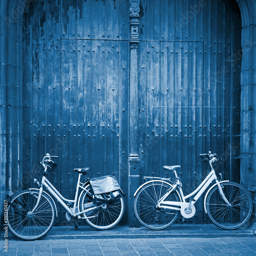 Bicycles leaning against wooden door blue toned
