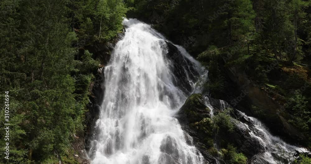 Establishing shot of the Schleierfall (veil fall), a huge waterfall in the Hohe Tauern nature reserve in the Austrian Alps in the valley of Kals am Großglockner. Establishing shot of the Schleierfall (veil fall), a huge waterfall in the Hohe Tauern nature reserve in the Austrian Alps in the valley of Kals am Großglockner.