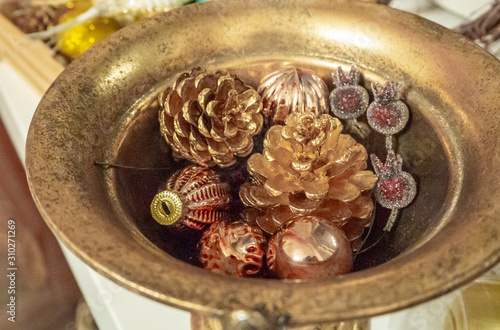 Christmas composition of gold pink balls, cones and berries in bronze bowl. Christmas and New year background