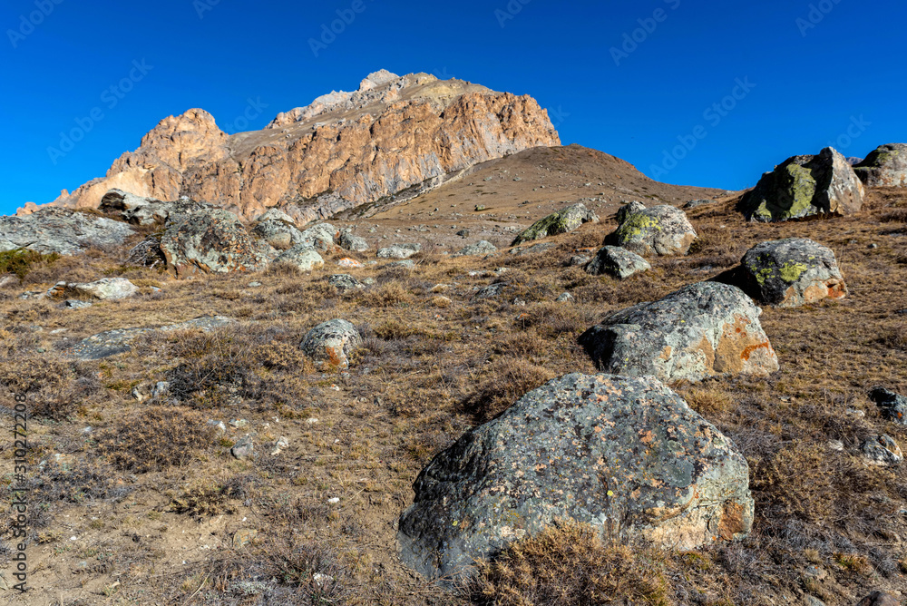 Rocks and dry grass in North Caucasus mountains in autumn on sunny day