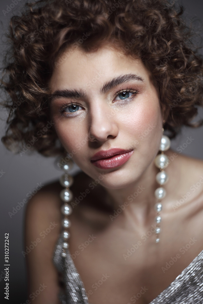 Vintage style portrait of young beautiful girl with curly hair and glossy party makeup, soft focus