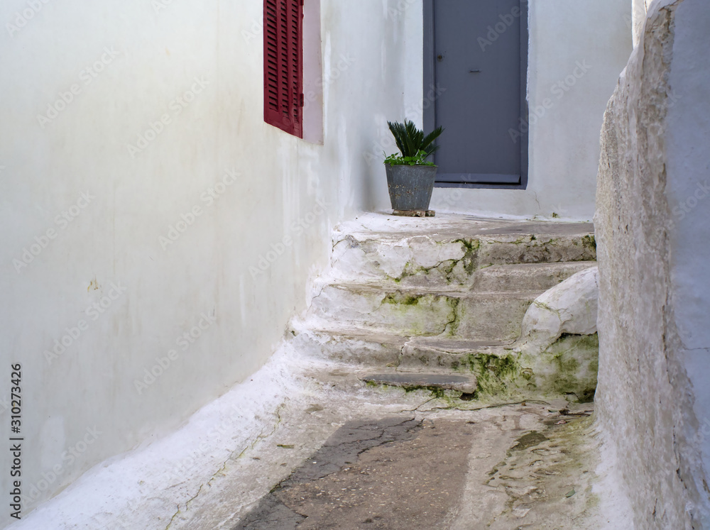Narrow alley between white walls in Anafiotika area on Acropolis slope, Athens, Greece.