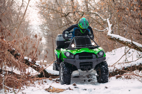Rider driving in the quadbike race in winter in the forest.
