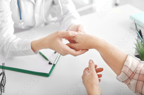 Tableau sur toile Doctor examining mature woman with joint pain in clinic, closeup