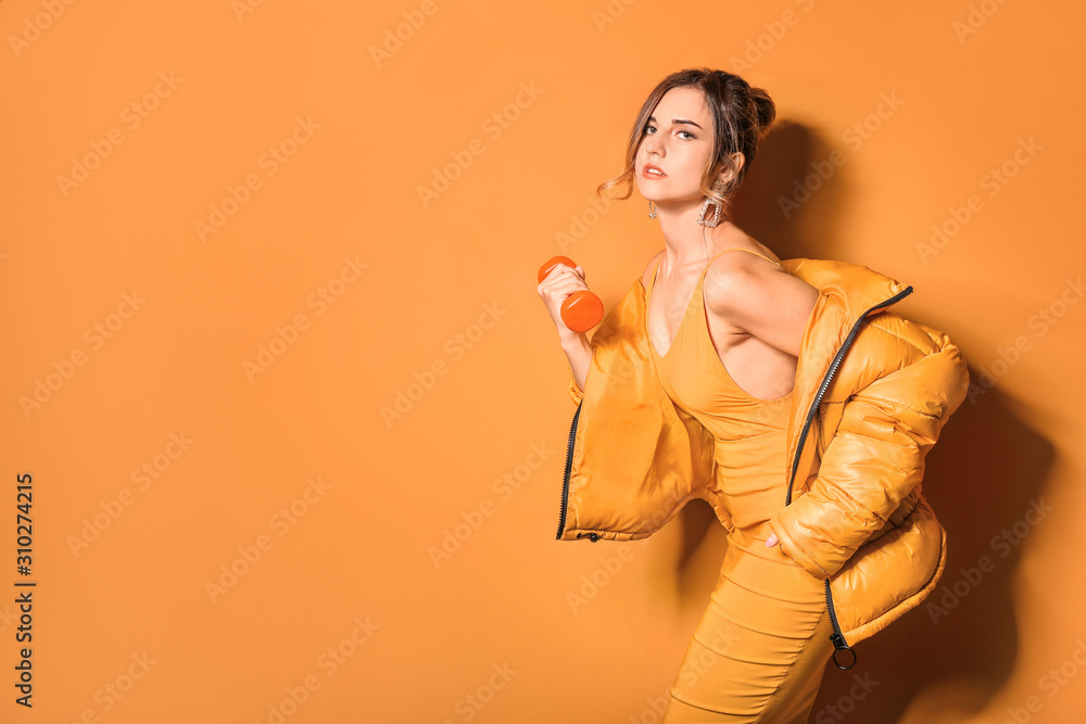Fashionable young woman with dumbbell on color background Fashionable young woman with dumbbell on color background