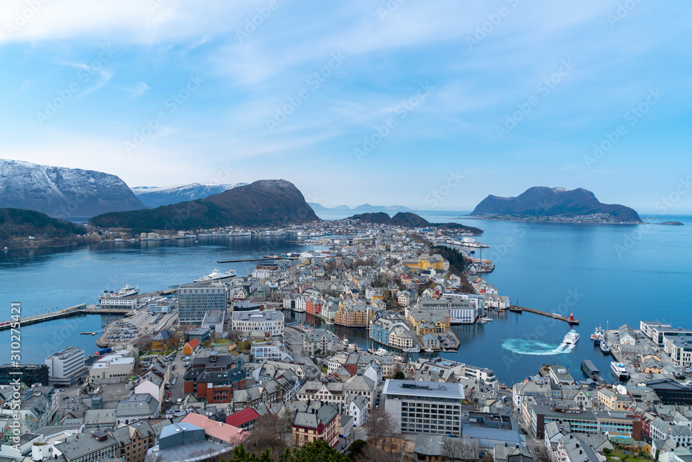 birds eye, aerial view over scandinavian city of Alesund and Harbor with a beautiful sight of the fjord of Alesund on a sunny day in spring with blue skies