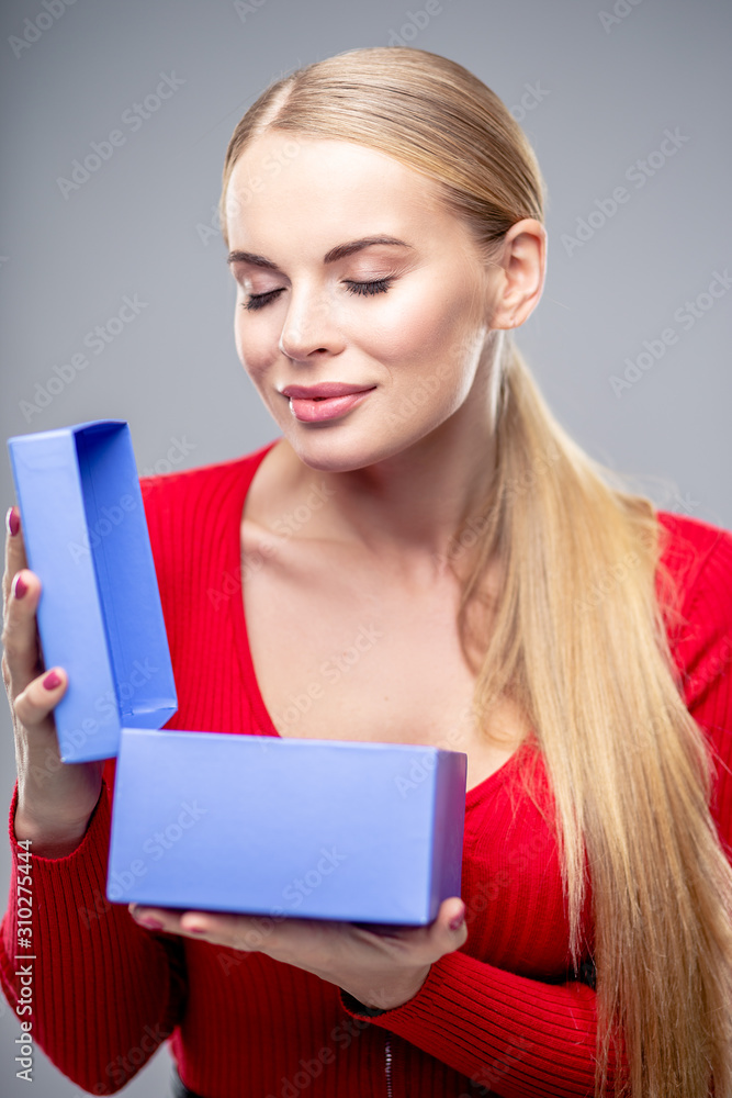 Young blonde woman with beautiful healthy long hair and natural make up holds a gift box. Fashion beauty portrait Young blonde woman with beautiful healthy long hair and natural make up holds a gift box. Fashion beauty portrait