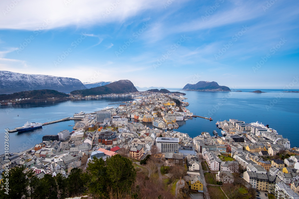birds eye, aerial view over scandinavian city of Alesund and Harbor with a beautiful sight of the fjord of Alesund on a sunny day in spring with blue skies
