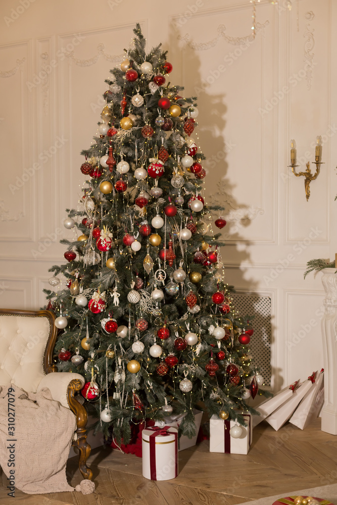 Christmas tree near the sofa in the room with a classic design.