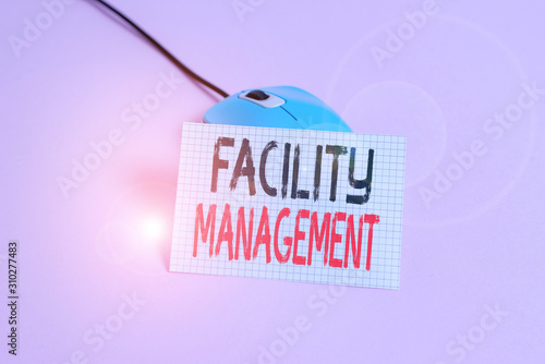 Writing note showing Facility Management. Business concept for maintenance of an organization s is buildings and equipment Wire vintage electronic mouse squared paper sheet colored background photo