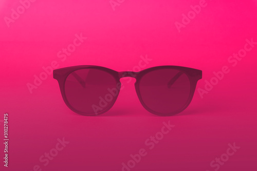Vintage sunglasses in pink lighting. Pink suglasses in minimal and summer concept background