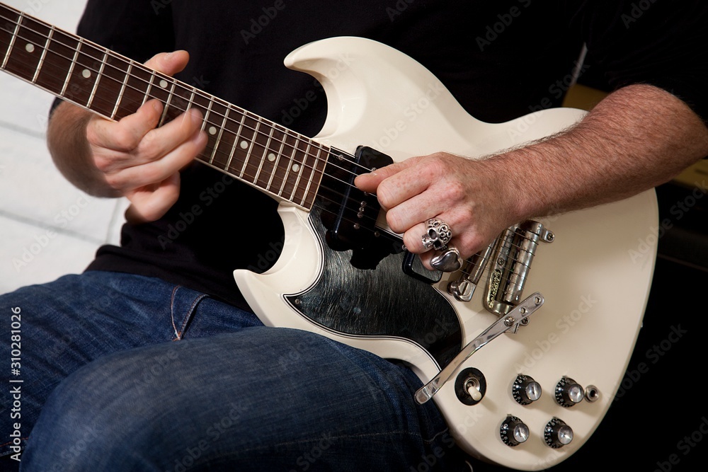 Close-up of mid adult man's torso playing guitar