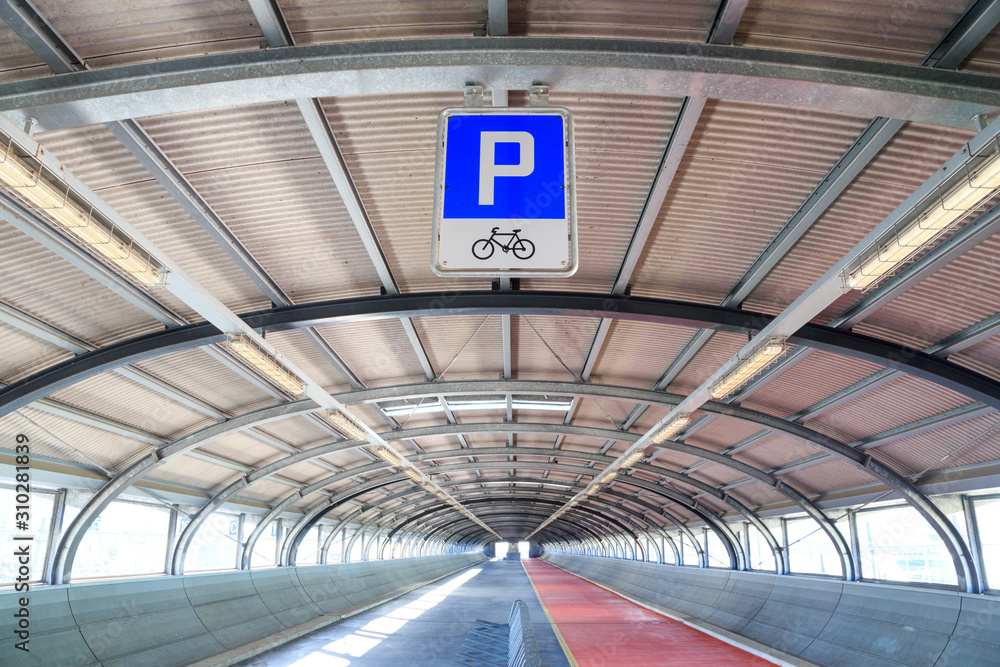 Bicycle parking overhead sign and ceiling of an empty corridor (overpass) for pedestrians and bikes designed in futuristic style, in Geneva, Switzerland. 