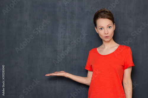 Portrait of surprised impressed girl pointing at copy space on left