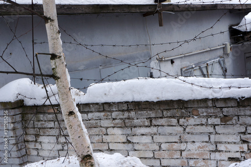 Barbed wire and snow on brick fence. photo