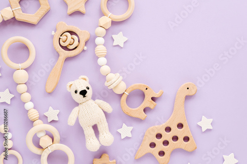 Cute wooden baby toys on light-blue background. Knitted bear,  dinosaur toy, beads and stars. Eco accessories,  beanbag and teethers for newborn. Flat lay, top view