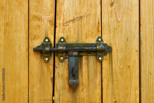 Iron latch and yellow wooden gate closeup on the ranch house for background or texture © soleg