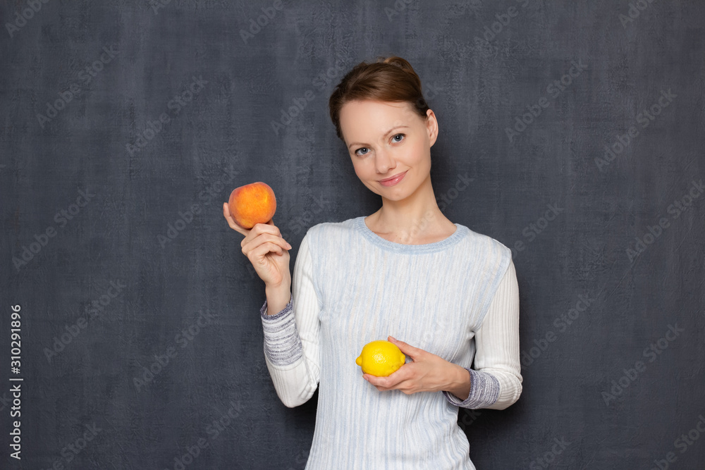 Portrait of happy girl smiling and holding lemon and peach in hands Portrait of happy girl smiling and holding lemon and peach in hands