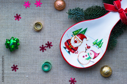 Christmas decorations. Decorative white tableware with the image of Santa Claus, snowman and Christmas trees. Chocolates in festive packaging. Ribbon for decoration. Christmas background.
