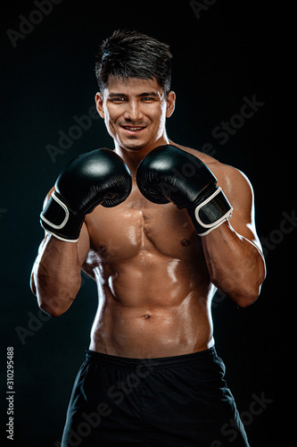 Fitness and boxing concept. Boxer, man fighting or posing in gloves on black background. Individual sports recreation. © Mike Orlov