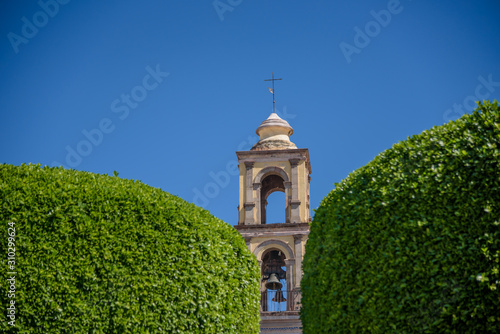 Close up of the top of a church temple in Queretaro Mexican town seen from between two green bushes