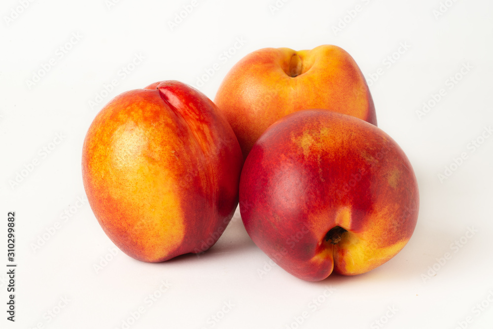 Three juicy orange nectarines close-up on a white background Three juicy orange nectarines close-up on a white background