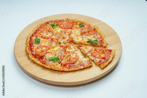 Pizza with slices of sausage, cheese and tomatoes, cut into rings. Pizza on a light wooden platter. 45 degree side view