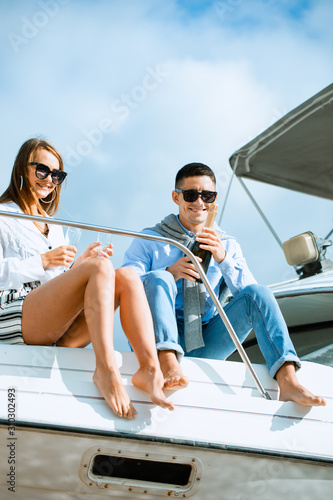 Man uncorking champagne and having party with wife on deck. © Air_Lady