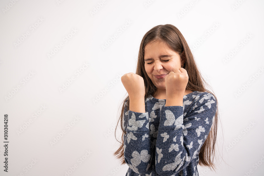 Waist up portrait of the beautiful brunette girl with loose hair dressed in blue shirt stands with clenched fists, emotions of success and trial Waist up portrait of the beautiful brunette girl with loose hair dressed in blue shirt stands with clenched fists, emotions of success and trial