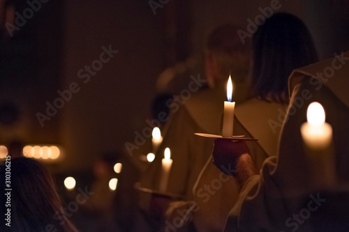 People are handling candles in the traditionall religious habit dresses in the church. Celebration of Lucia day  Sweden