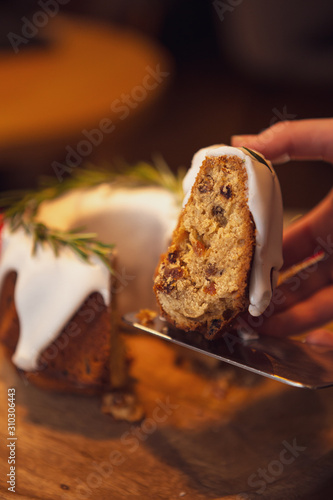 decorated Christmas cake - Traditional European Christmas pastry, fragrant home baked stollen, Sliced on wooden table with xmas tree branches and decorations
