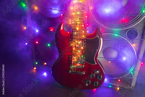 abstract guitar with festive Christmas lights and music speakers in smoke