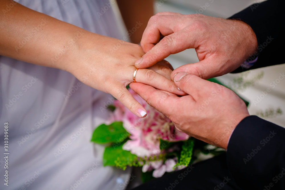 Groom putting wedding ring on bride's finger during the wedding ceremony Groom putting wedding ring on bride's finger during the wedding ceremony