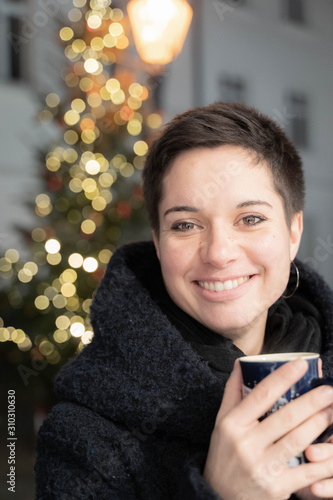 Portrait of a young woman on a christmas market in Germany with a cup of mulled wine
