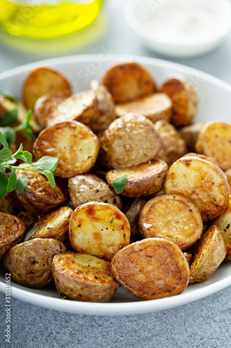 Fotografija Roasted or air fryed baby potatoes with oil and herbs in a bowl
