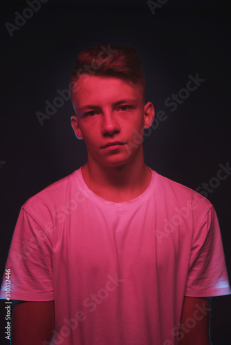 Slender young guy posing in neon red and blue light