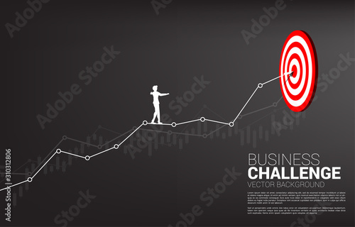 silhouette of businessman walk rope on line graph to center of dartboard. Concept of targeting and Business challenge.route to success.