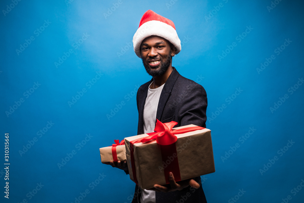 Portrait of an excited young african man holding many gifts, isolated on blue background Portrait of an excited young african man holding many gifts, isolated on blue background