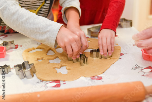 Boy and a girl making gingerbread decorations together with cutting out shapes and figures of different kind