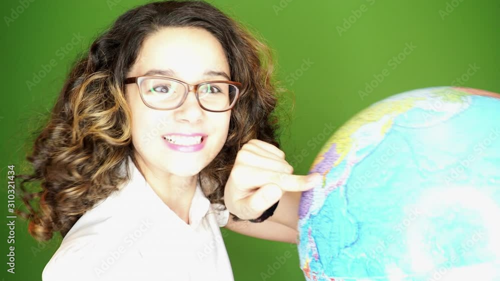 Attractive curly-haired dark-haired teenager with glasses in a white blouse using her globe and with surprised looking at camera, indoor isolated shot. 4k Attractive curly-haired dark-haired teenager with glasses in a white blouse using her globe and with surprised looking at camera, indoor isolated shot. 4k