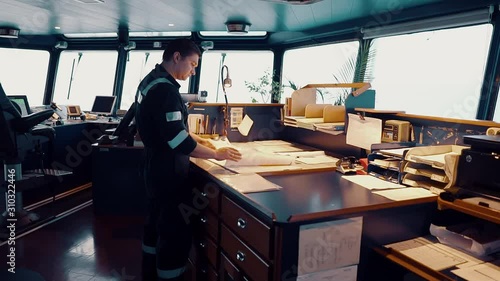 Marine navigational officer during navigational watch on Bridge . He does chart correction of nautical maps and publications. Work at sea photo