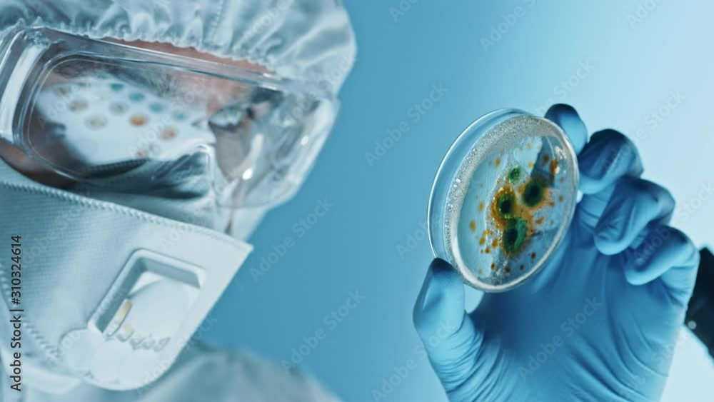 Scientist Wearing Respirator Mask, Coverall and Safety Glasses Looks at