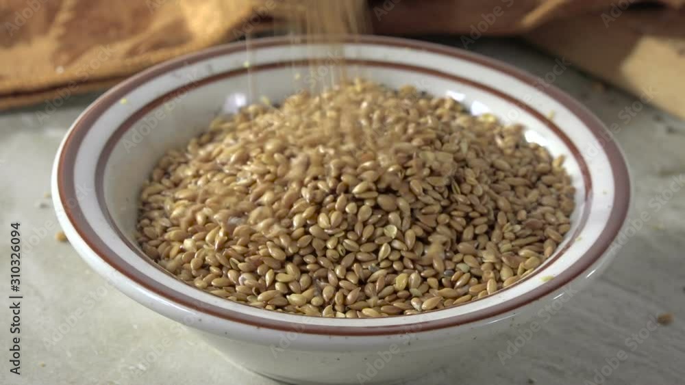 Pouring golden roasted flax seeds into a small bowl Pouring golden roasted flax seeds into a small bowl