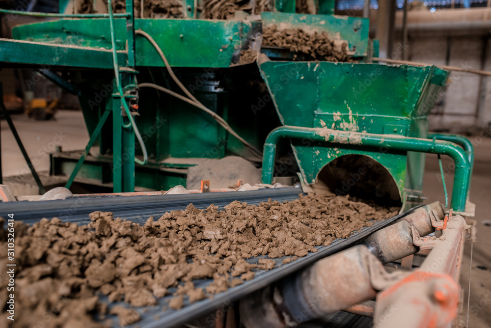 Obraz premium Plant for the production of bricks from clay. Plant for production building material with ready brick, construction industrial. Production of bricks on plant. Workflow, close-up. Many bricks