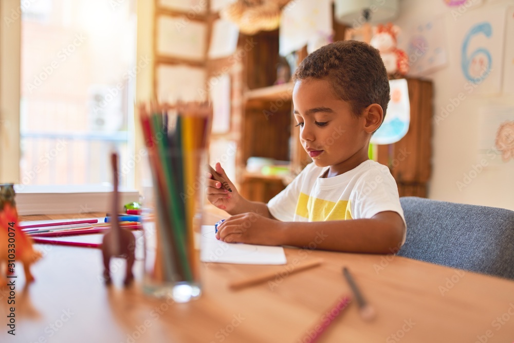 Beautiful african american toddler sitting painting car toy using marker pen on desk at kindergarten - obrazy, fototapety, plakaty 