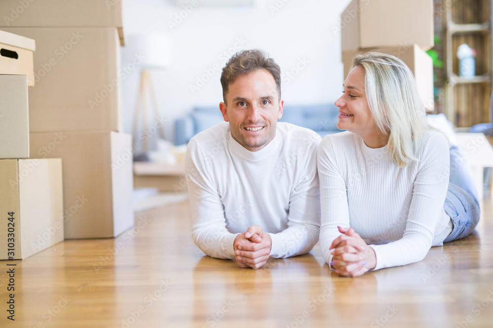Young beautiful couple lying down on the floor at new home around cardboard boxes Young beautiful couple lying down on the floor at new home around cardboard boxes